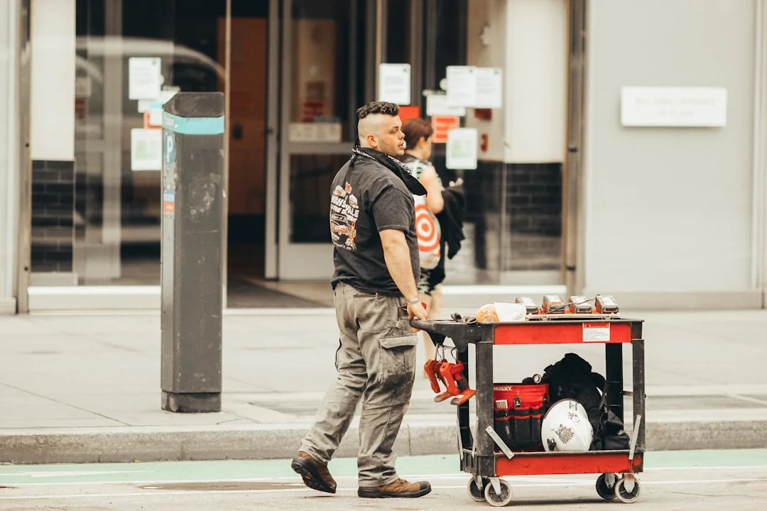 A professional cleaner in a red uniform holding a vacuum near a van, ready for service.
